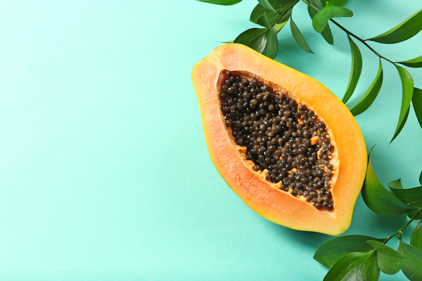 Halved papaya with leaves on blue background